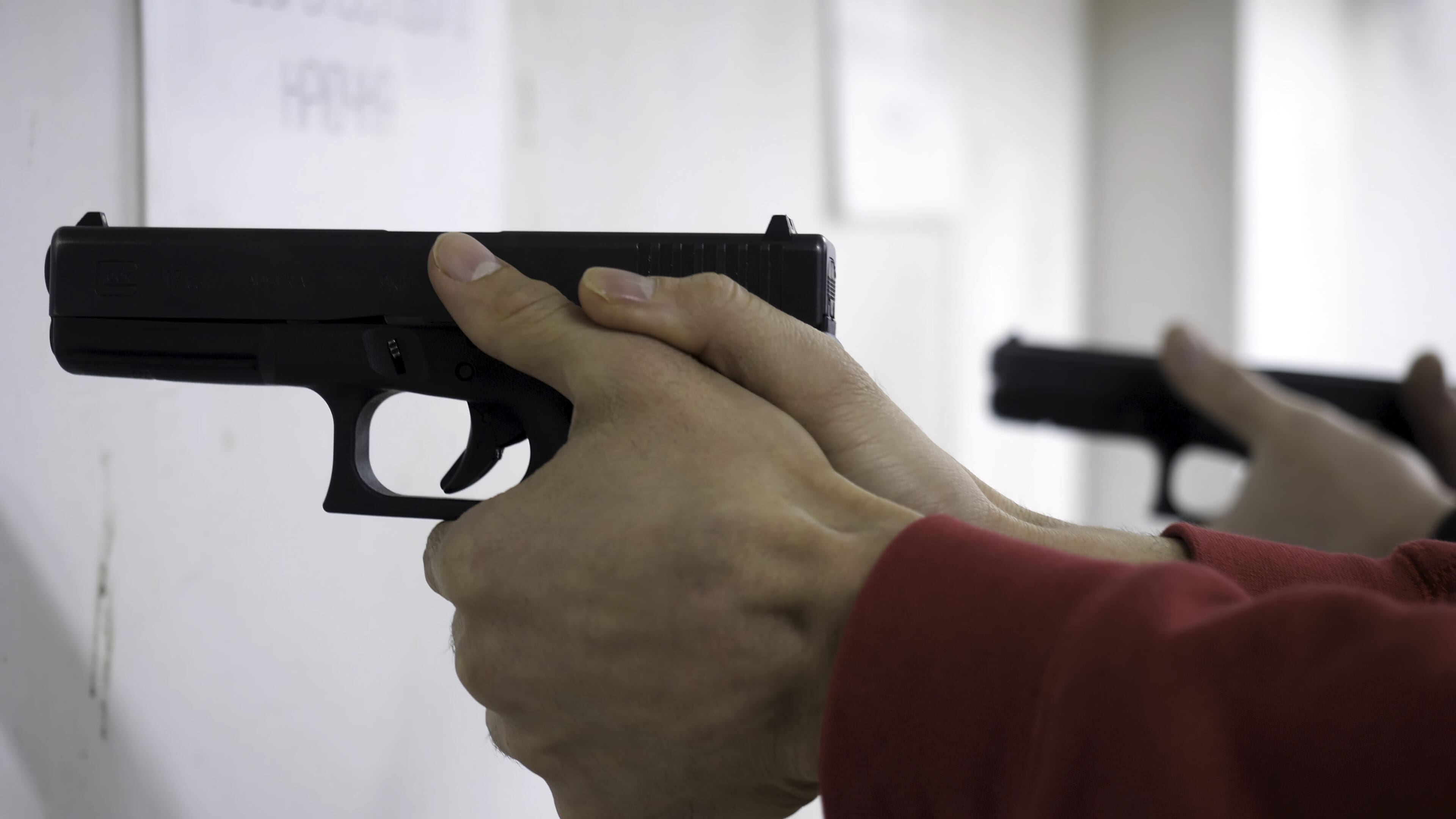 Instructor teaches a man to handle a weapon or gun. Close up of male hands with gun while training with instructor. Close up of man's hand reloading gun.