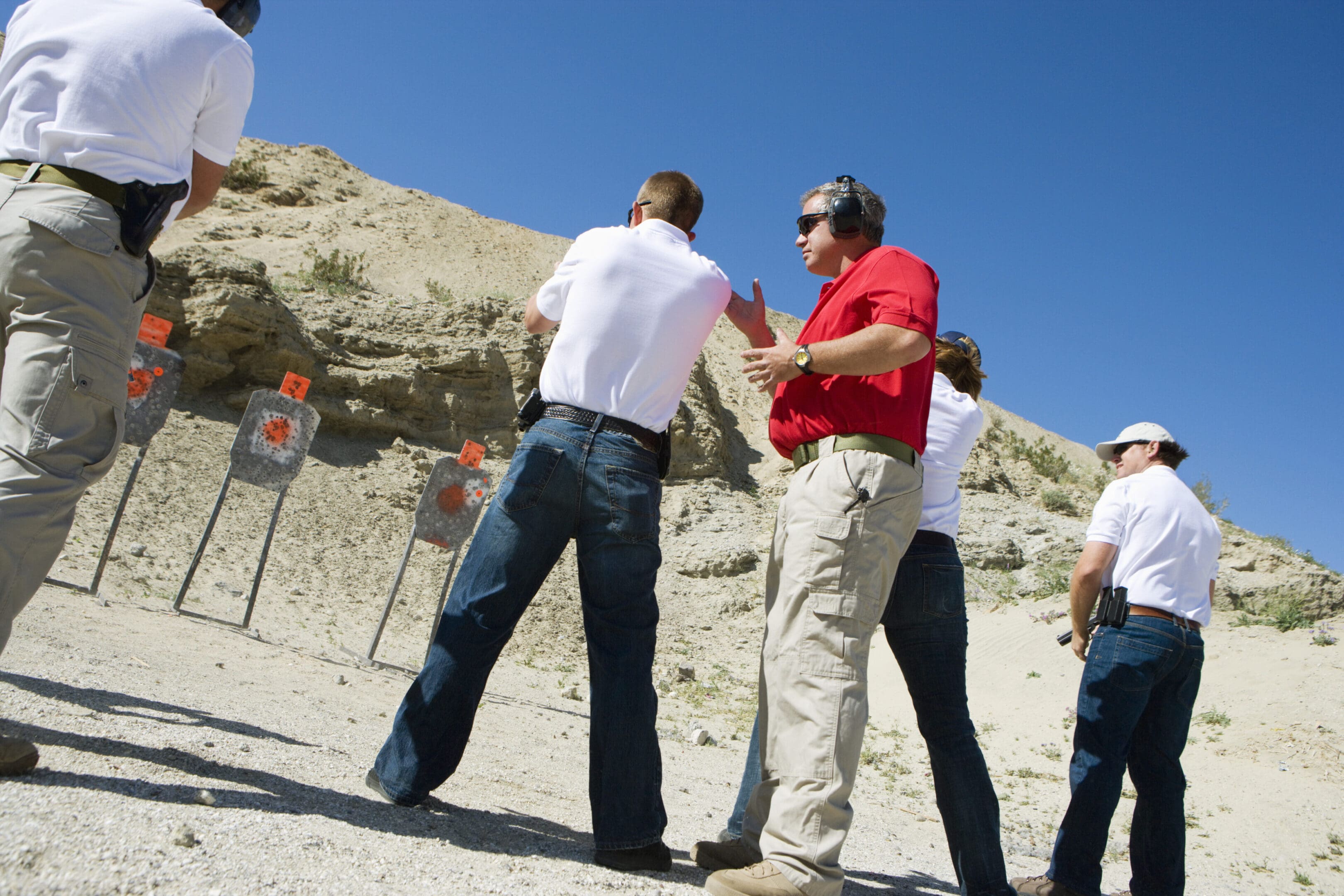 Instructor assisting people aiming guns at firing range